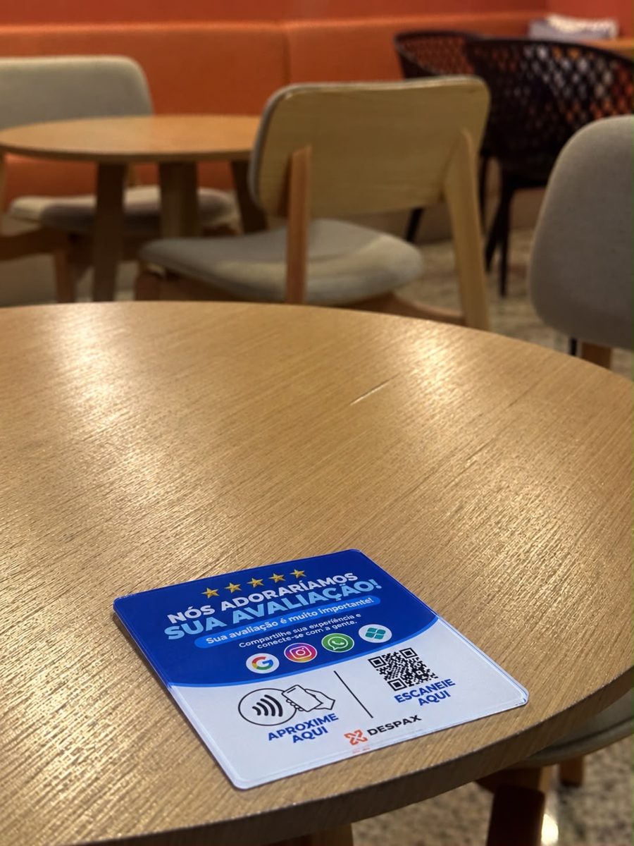 Placa NFC DESPAX CONNECT em acrílico sobre mesa de café, com Google, Instagram, WhatsApp e Pix