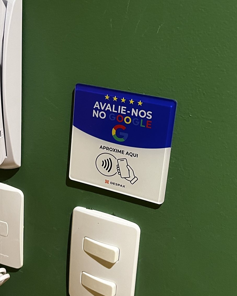 Placa NFC DESPAX REVIEW em acrílico instalada na parede, ao lado do interfone