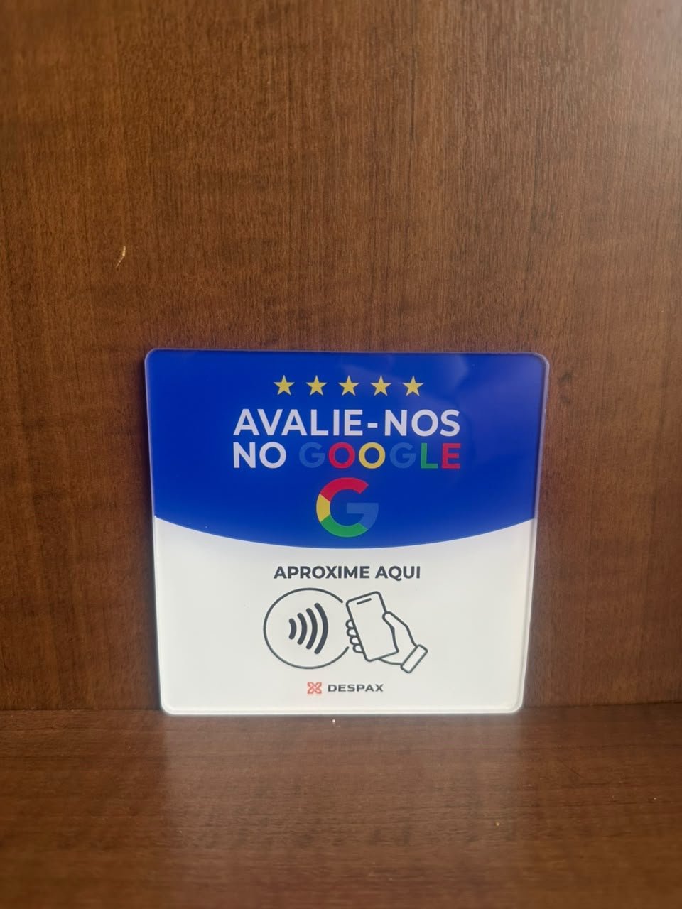 Placa NFC DESPAX REVIEW em acrílico para avaliações no Google, apoiada sobre móvel de madeira
